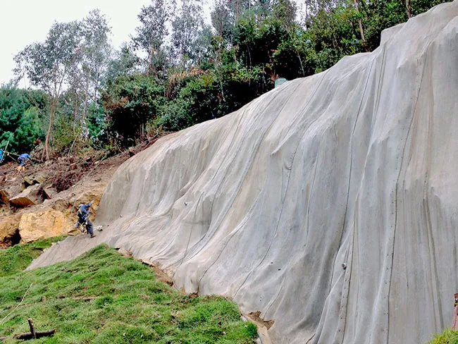 Técnico con arnés hidratando un talud empinado revestido con manto